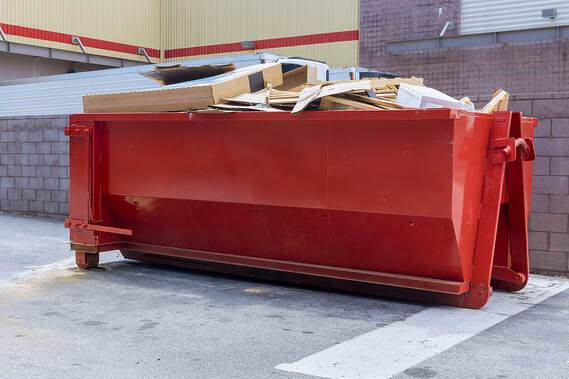 In White Plains, NY, a rubbish removal container on the house underneath an industrial building is used for waste disposal at a construction site.