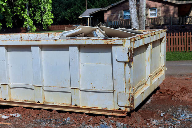 At a White Plains, NY, construction site, a rubbish removal container on the house underneath an industrial building is used for waste disposal.