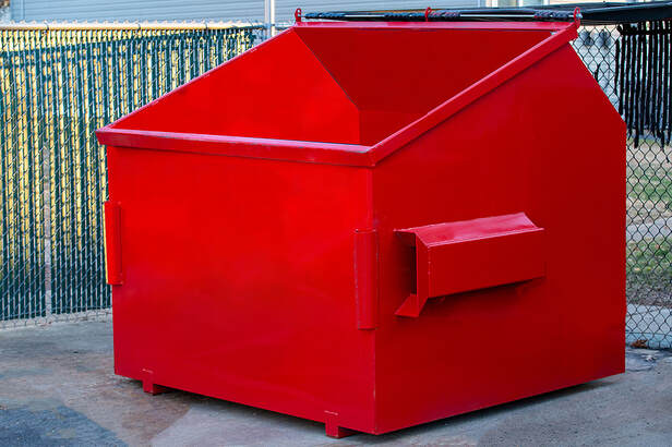In White Plains, NY, a durable metal industrial trash dumpster is used for outdoor trash disposal and is colored red for ecology.Picture