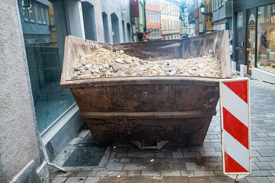 In the shopping street of White Plains, NY, there is a container filled with rubble.