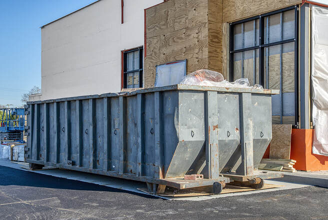 A big, heavy-duty dumpster in White Plains, NY, sits under construction next to a new fast-food restaurant.