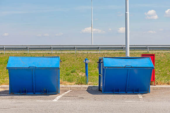 Two big blue trash dumpster containers are at a White Plains, NY, highway stop.