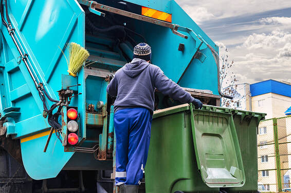 In a residential area of White Plains, NY, a garbage truck picks up garbage for removal.