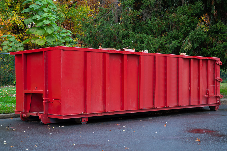 A metal trash construction garbage dumpster is used for waste disposal on a house renovation industry material outdoor project in White Plains, NY.